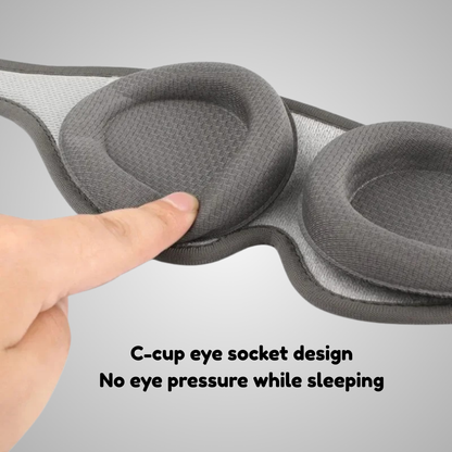 Rest'd Gray eye mask with a C-cup design, showing a hand pressing on it, on a gray background.